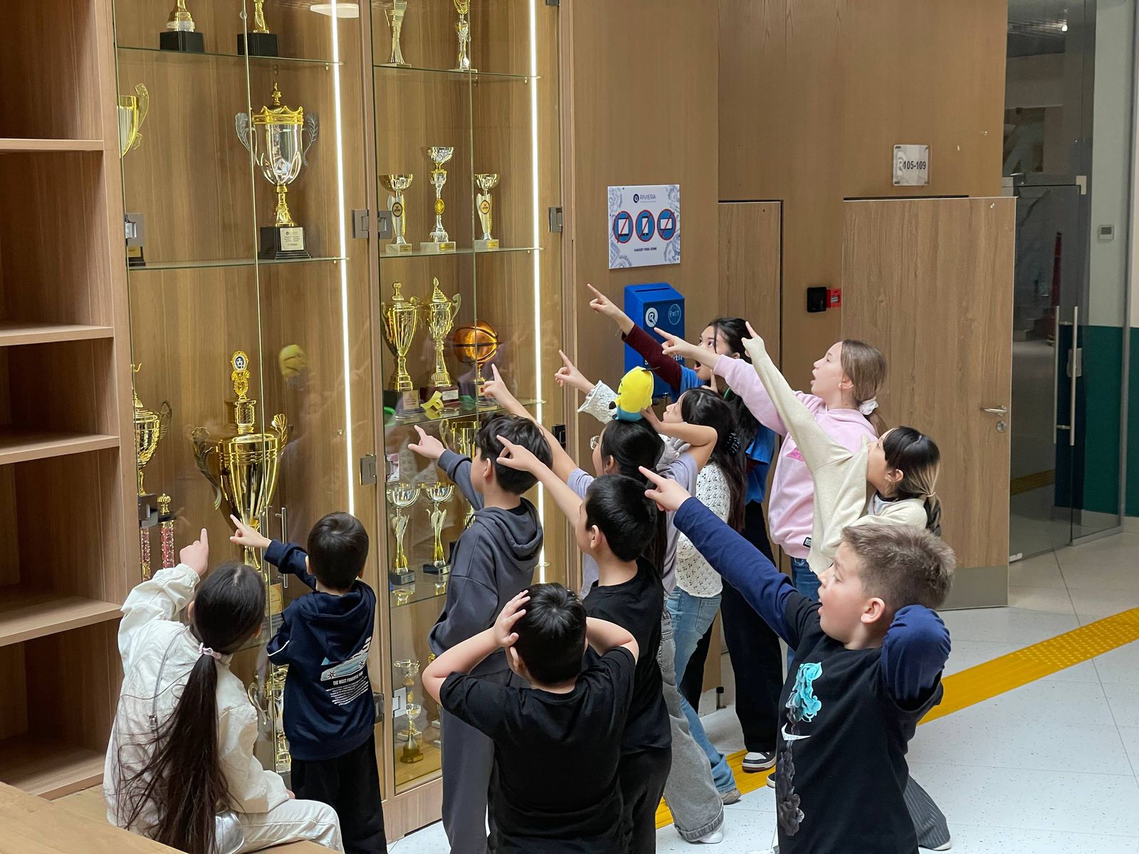 Дети показывают пальцами на золотые кубки